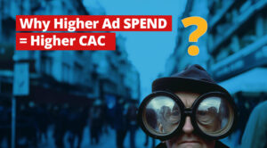 Why is scaling ads so expensive? 1 White text on red says: Why Higher Ad Spend = Higher CC over an AI photo of a man with comically oversized glasses standing in a street staring at us with pedestrians walking around in the blurry background